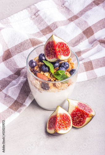 Obraz na płótnie Healthy breakfast homemade yogurt with berries, granola and figs. Glass of yogurt on gray background w salonie