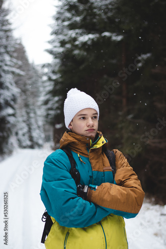 Candid portrait of a young man wearing a winter coloured jacket and a white cap during the winter season in a snowy area. Exploring new areas