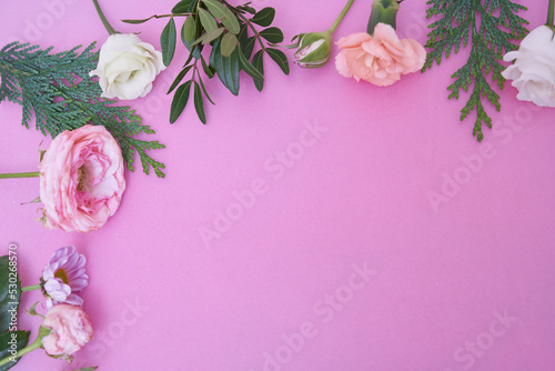 View from above. Part of a close-up frame of fresh flowers rose, ranunculus, carnation, juniper, eustoma, bush chrysanthemum, on a pink background. With a space to copy. High quality photo