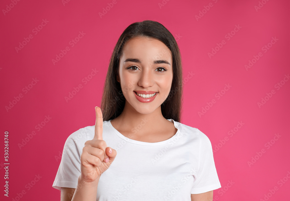 Woman showing number one with her hand on pink background Woman showing number one with her hand on pink background