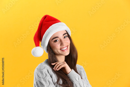 Beautiful woman wearing Santa Claus hat on yellow background © New Africa