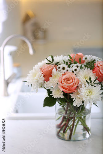 Vase with beautiful flowers on countertop in kitchen. Interior design