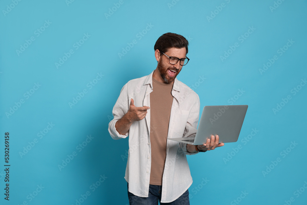 Handsome man with laptop on light blue background Handsome man with laptop on light blue background