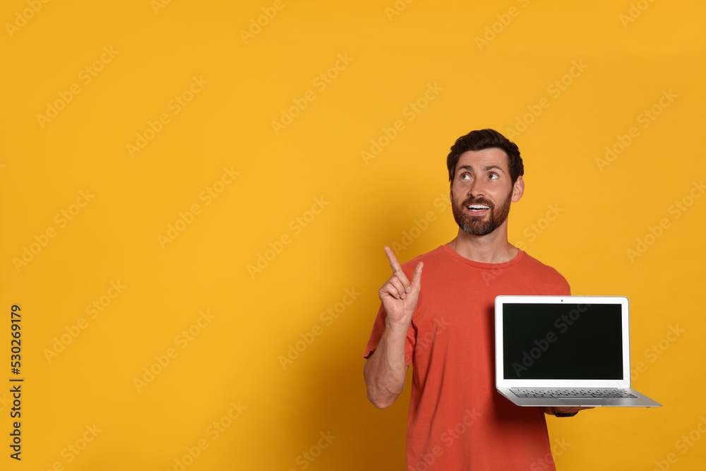 Handsome man with laptop on orange background Handsome man with laptop on orange background