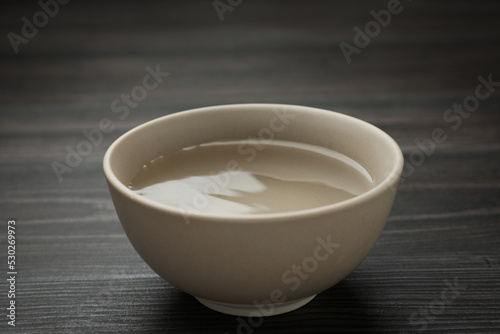 Beige bowl with water on dark wooden table
