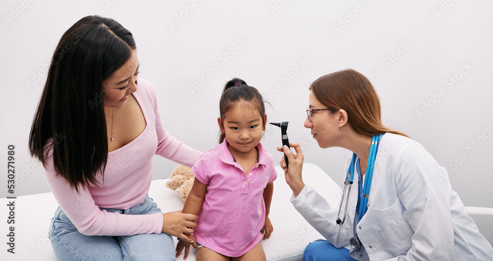 Korean child with her mother during hearing test, audiologist with otoscope checking ear of asian little girl. Hearing exam Korean child with her mother during hearing test, audiologist with otoscope checking ear of asian little girl. Hearing exam