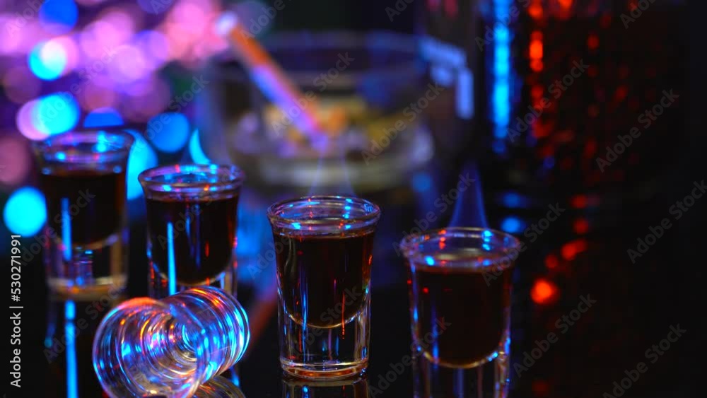 Rum in stacks on the bar counter. Strong alcohol burns in drinks on the background of the bar. Relax in the bar with strong drinks. Fire in the glasses with alcohol.