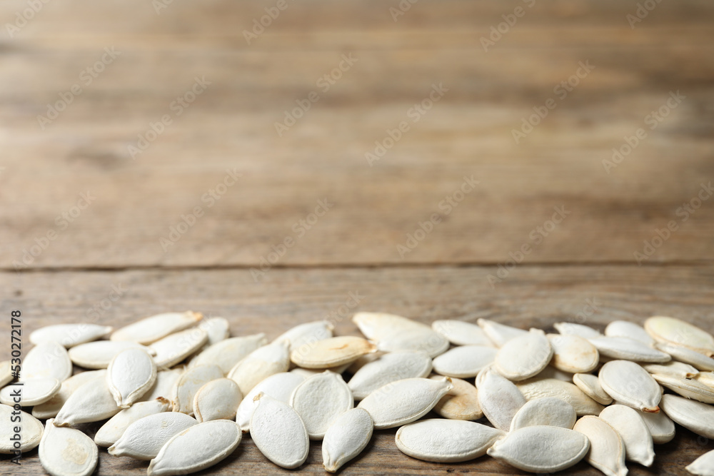 Raw pumpkin seeds on wooden background, space for text. Vegetable planting