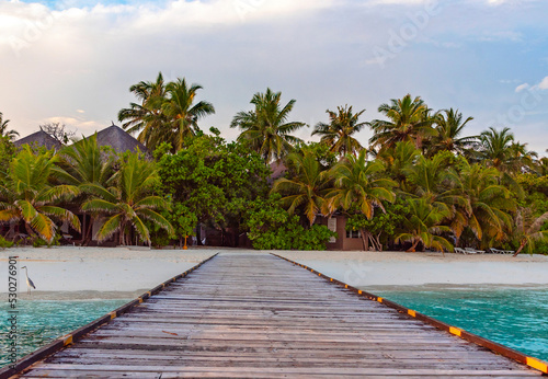 pier leading to the island at sunrise in the Maldives, the concept of luxury travel © klavdiyav