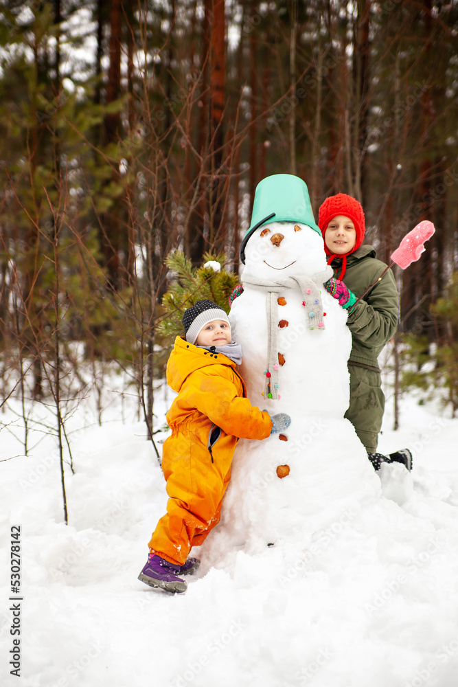 Two sisters make a snowman in winter