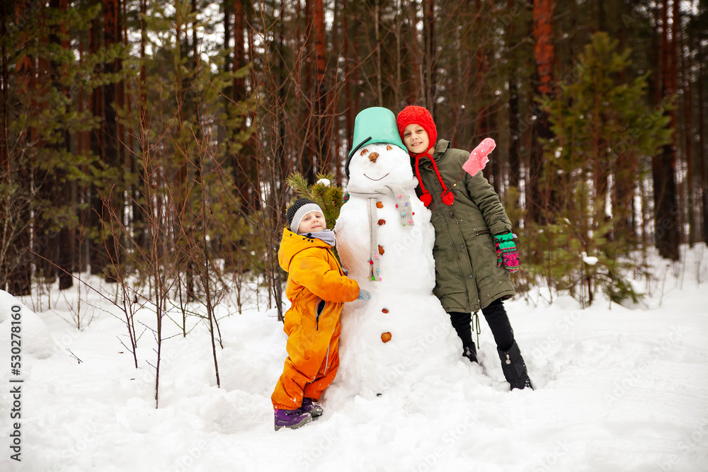 Two sisters make a snowman in winter