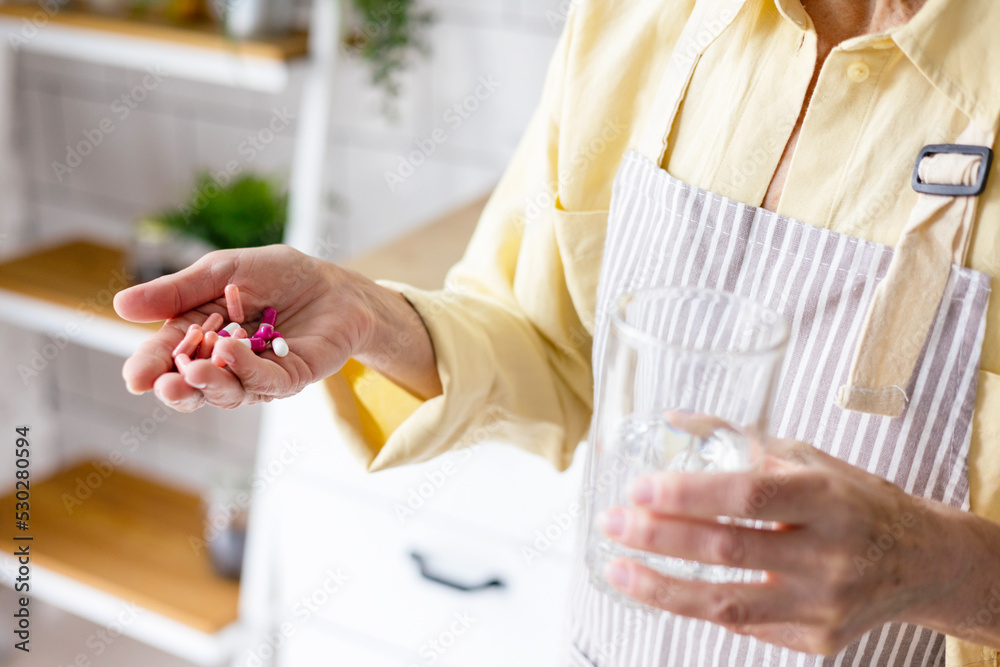 beautiful elderly grey haired senior woman in cozy kitchen takes vitamin supplement in capsule, drinks pure water from glass, biologically active food additives for full life, healthy food active life beautiful elderly grey haired senior woman in cozy kitchen takes vitamin supplement in capsule, drinks pure water from glass, biologically active food additives for full life, healthy food active life