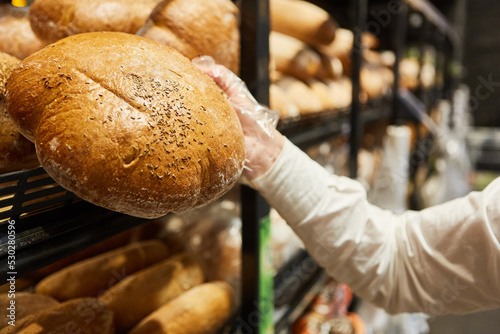 Hand eines Kunden nimmt Laib Brot aus dem Regal photo