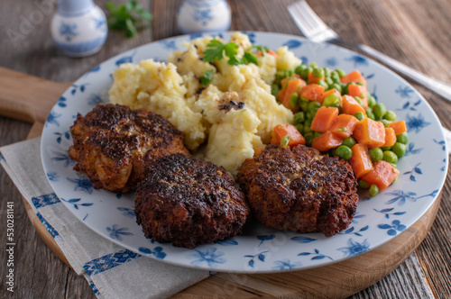 Pork meatballs with mashed potatoes and peas and carrot vegetables.