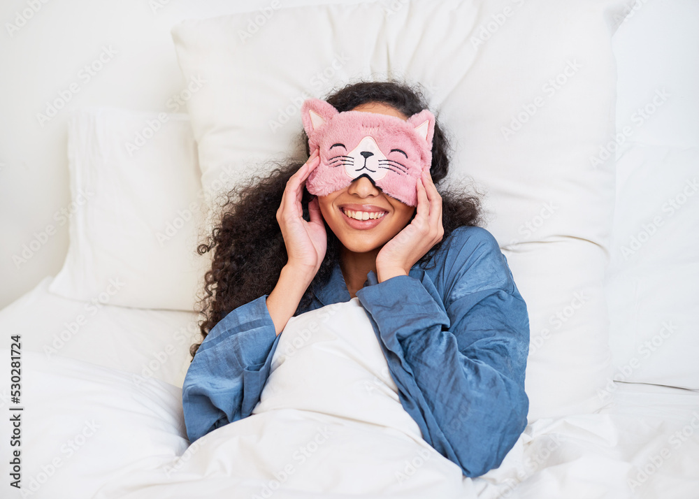 © Meeko Media - A young multi-ethnic woman wakes up in bed with a cute kitten sleep mask © Meeko Media - A young multi-ethnic woman wakes up in bed with a cute kitten sleep mask