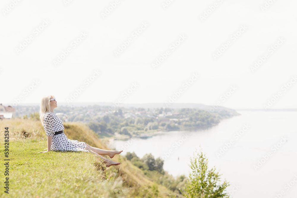 a girl in a white dress with black polka dots on the Sovereign's Mountain above the Volga River near the city of Mariinsky Posad