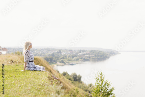 Fototapeta Naklejka Na Ścianę i Meble -  a girl in a white dress with black polka dots on the Sovereign's Mountain above the Volga River near the city of Mariinsky Posad
