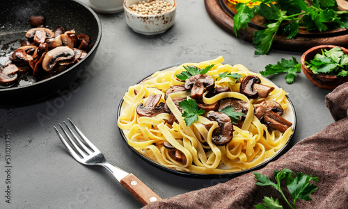 Photo Tasty tagliatelle pasta with mushrooms served on plate with parsley and spices on grey stone kitchen table background, top view