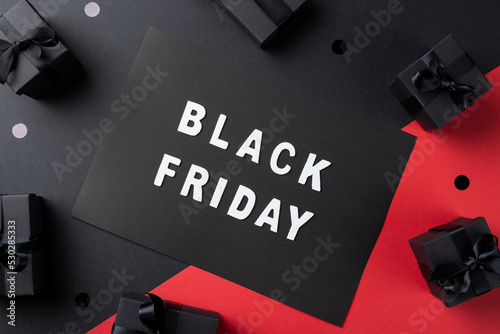 Composition of presents and black friday text on gray and pink background