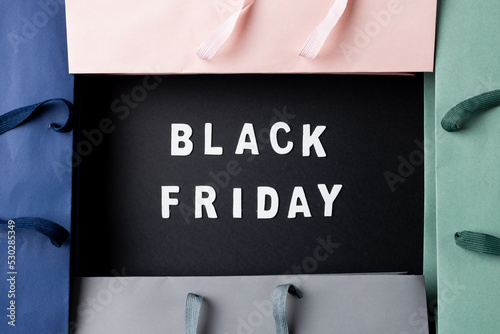 Composition of colourful shopping bags with black friday text on gray background