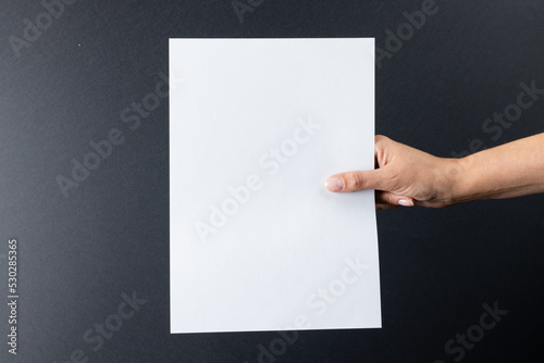 Composition of hand holding blank card with copy space on gray background