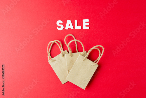 Composition of sale text and paper shopping bags on pink background