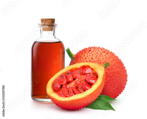 Gac fruit oil with fresh fruits isolated on white background. photo