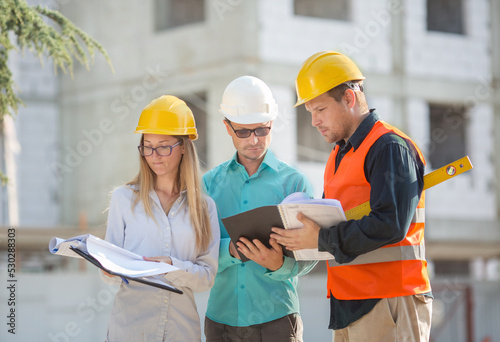 an engineer, an accountant, an estimator and a foreman worker confer about drawing up an estimate and a project for the construction of a multi-storey building.