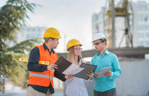 an engineer, an accountant, an estimator and a foreman worker confer about drawing up an estimate and a project for the construction of a multi-storey building..