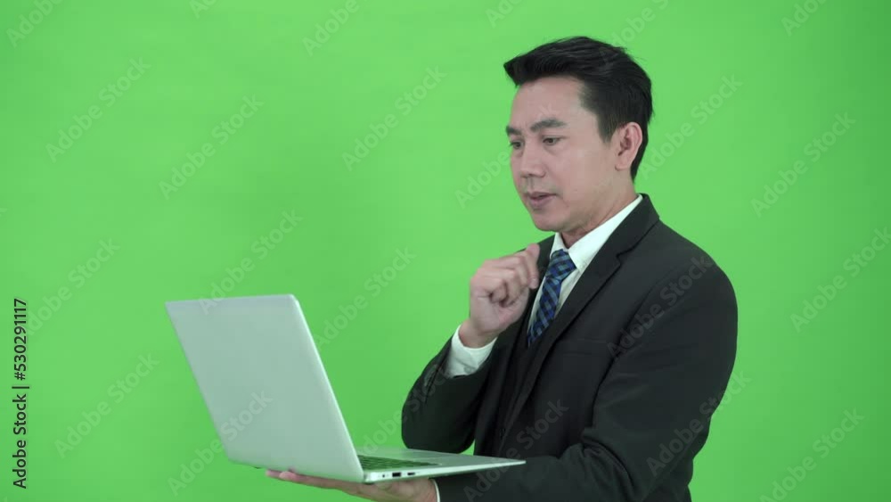 Asian businessman turning on laptop computer on chroma green screen. Asian businessman turning on laptop computer on chroma green screen.