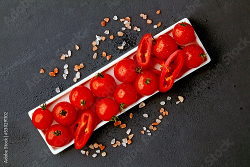 Fresh washed cherry tomatoes and paprika slices on a white oblon photo