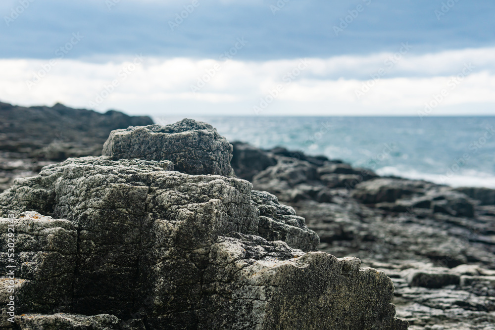 gray basalt rocks against a blurred stormy seascape
