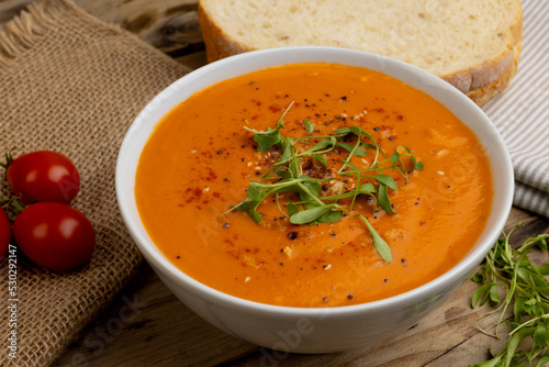Obraz na plátně Horizontal image of bowl of tomato soup with garnish, tomatoes and sliced bread