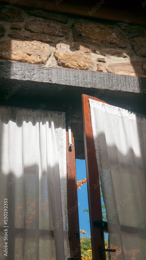 Cortinas blancas en puertas de madera de casa de piedra