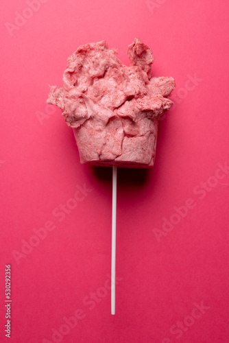 Vertical image of homemade pink candy floss on stick, on pink background with copy space