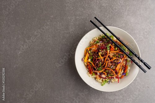 Overhead view of asian wok stir fry and chopsticks with copy space on grey background