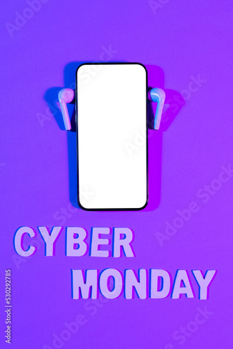 Image of cyber monday text, smartphone with blank screen and earphones on purple background