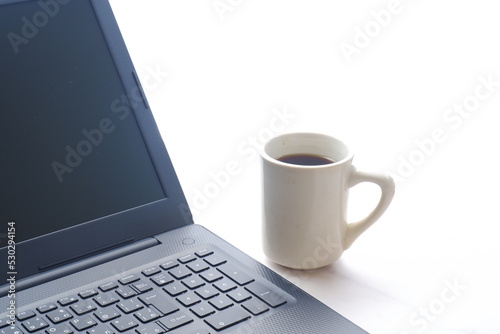 コーヒーを飲みながらノートパソコン（黒）で仕事をする