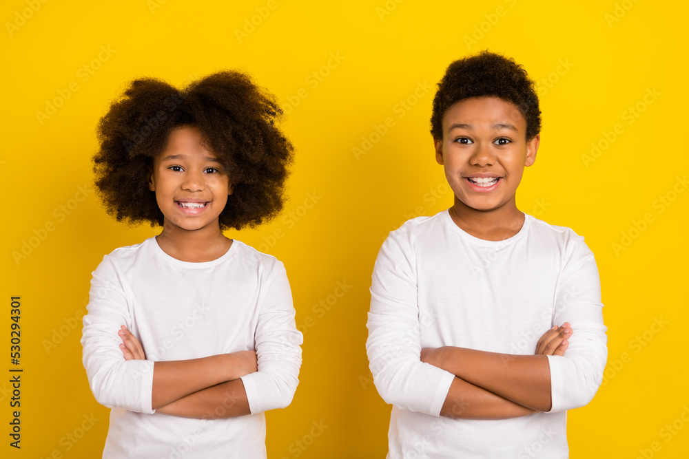 Photo of funny pretty schoolkids dressed white shirts arms crossed isolated yellow color background Photo of funny pretty schoolkids dressed white shirts arms crossed isolated yellow color background