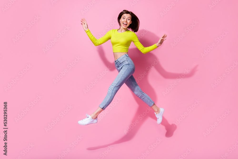 Full length photo of an overjoyed satisfied funky cheery slim skinny girl walking jumping isolated on bright pink color background