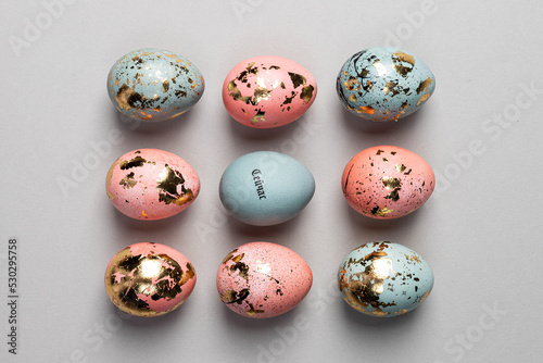 top view pattern nine spring easter eggs blue pastel pink with gold on grey background flat lay