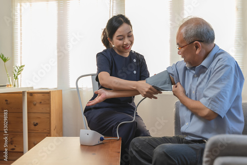 Nurse care service for retirement people, professional female caregiver measuring blood pressure senior man at home. © Pormezz