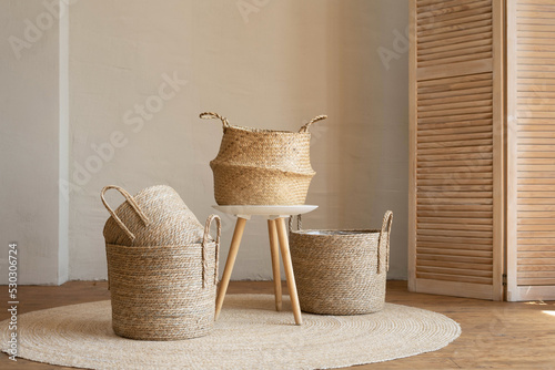 Various wicker baskets for interior decoration stand on the floor in a modern living room.
