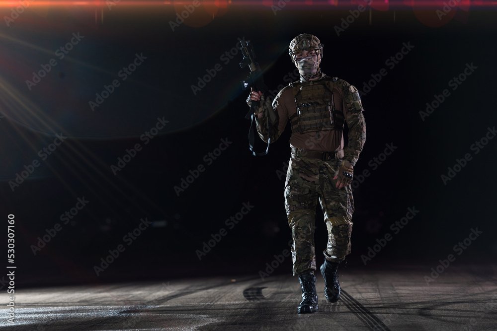 Army soldier in Combat Uniforms with an assault rifle, plate carrier and combat helmet going on a dangerous mission on a rainy night. Army soldier in Combat Uniforms with an assault rifle, plate carrier and combat helmet going on a dangerous mission on a rainy night.