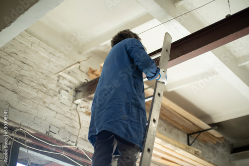 Wallpaper Mural Guy is standing on stairs. Worker hangs chain on steel beam. Construction staircase. Torontodigital.ca