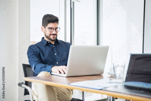 Businessman using laptop during video conference in a modern office