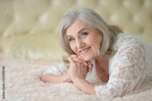 Thoughtful nice senior woman lying on bed