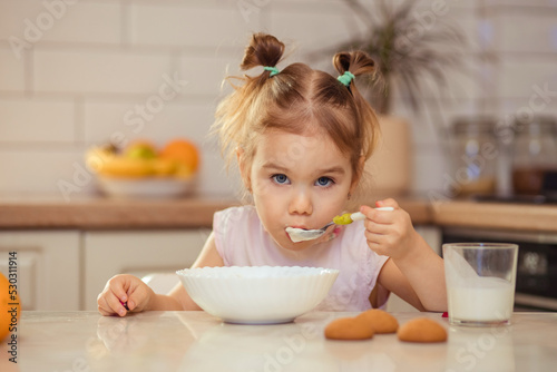 Happy little girl child 2-3 years old eats healthy food at home or in kindergarten.