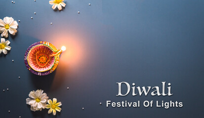 Happy Diwali - Clay Diya lamps lit during Diwali, Hindu festival of lights celebration. Colorful traditional oil lamp diya on blue background