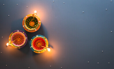 Happy Diwali - Clay Diya lamps lit during Diwali, Hindu festival of lights celebration. Colorful traditional oil lamp diya on blue background